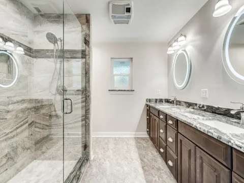 Remodeled bathroom with a glass walk-in shower and dark vanity